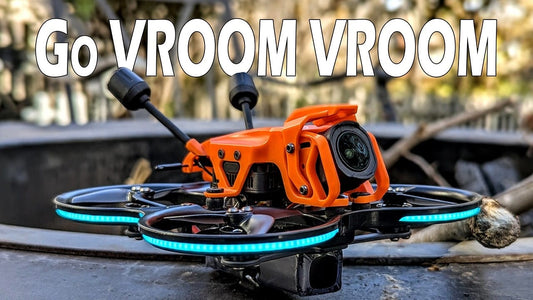A person holding the DarkStar22 O4 Pro micro whoop with its orange canopy.
