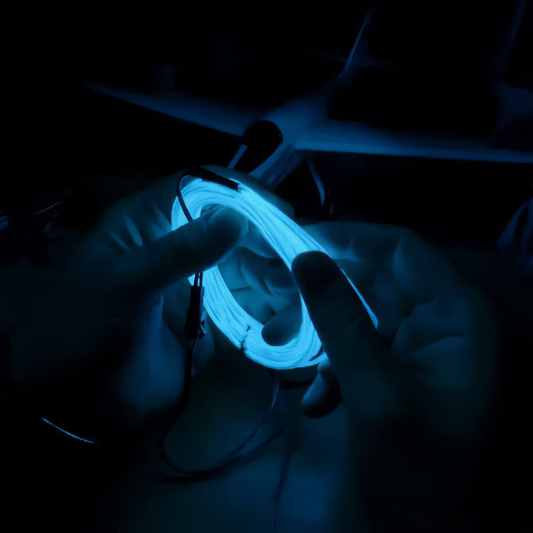 A close up of glowing blue EL wire coiled up in someone's hands.