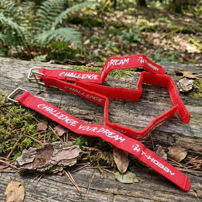 Red wristbands with 'Challenge Your Dream' text on a wooden log in a forest setting